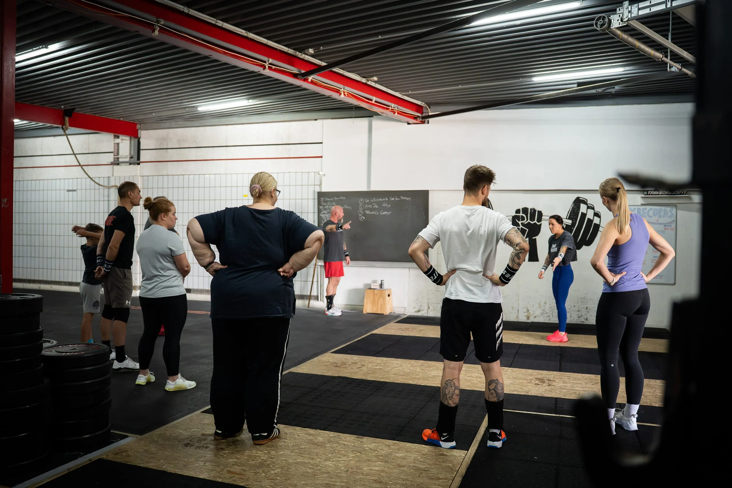 Coach erklärt der Gruppe die Stunde an der Tafel in der Trave CrossFit Box