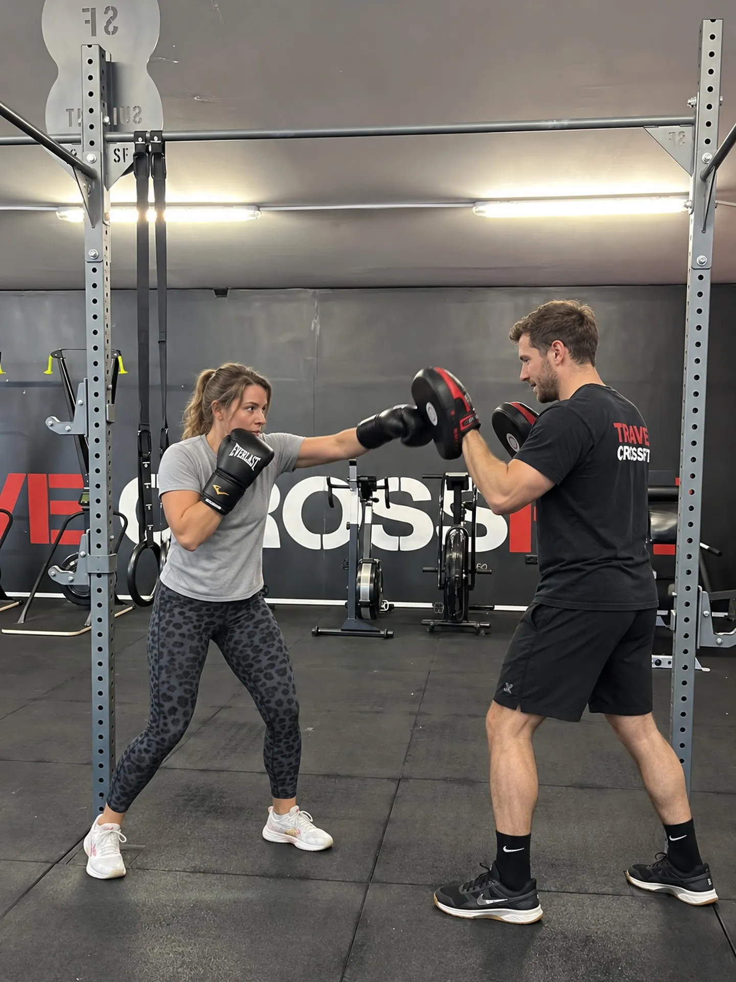 Athlete punching focus mitts held by a coach during fitness boxing at the Trave CrossFit box