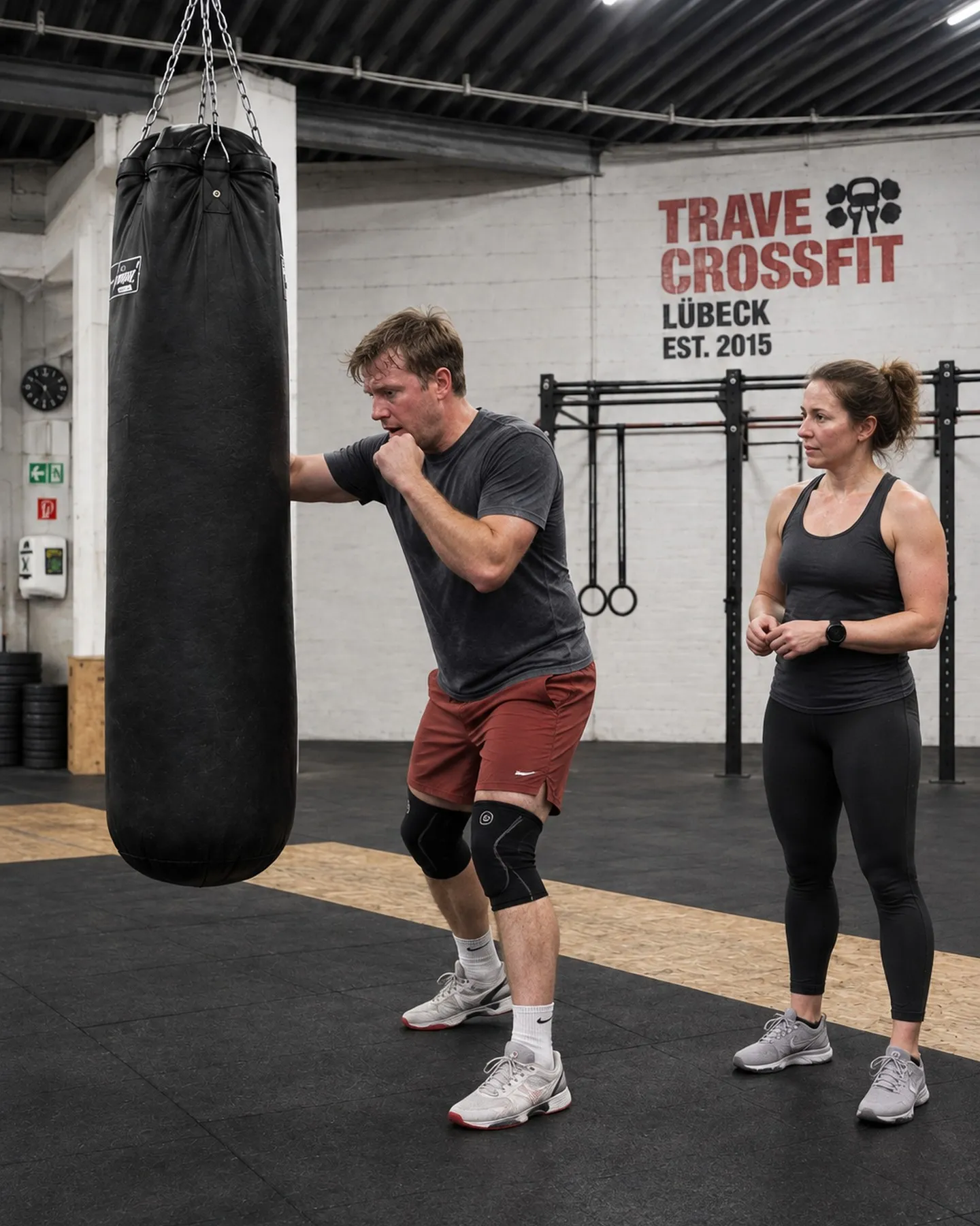 Man on the heavy bag with a coach at the Trave CrossFit box