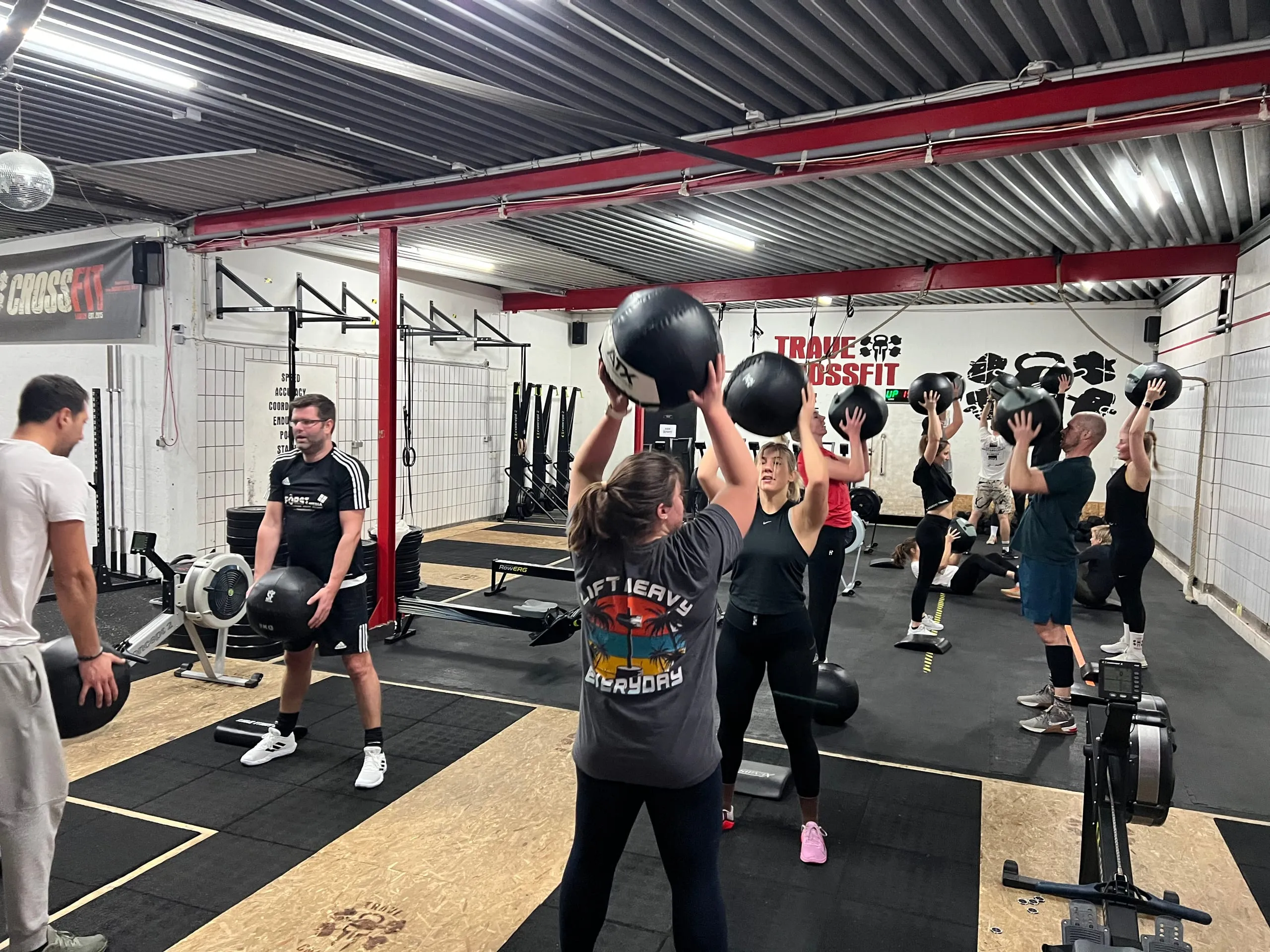 Group pressing wall balls overhead, coach in the foreground