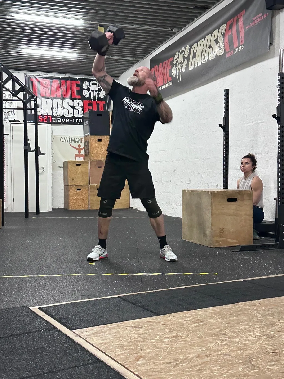 Sportler beim einarmigen Kurzhantel-Überkopfheben in der Trave CrossFit Box