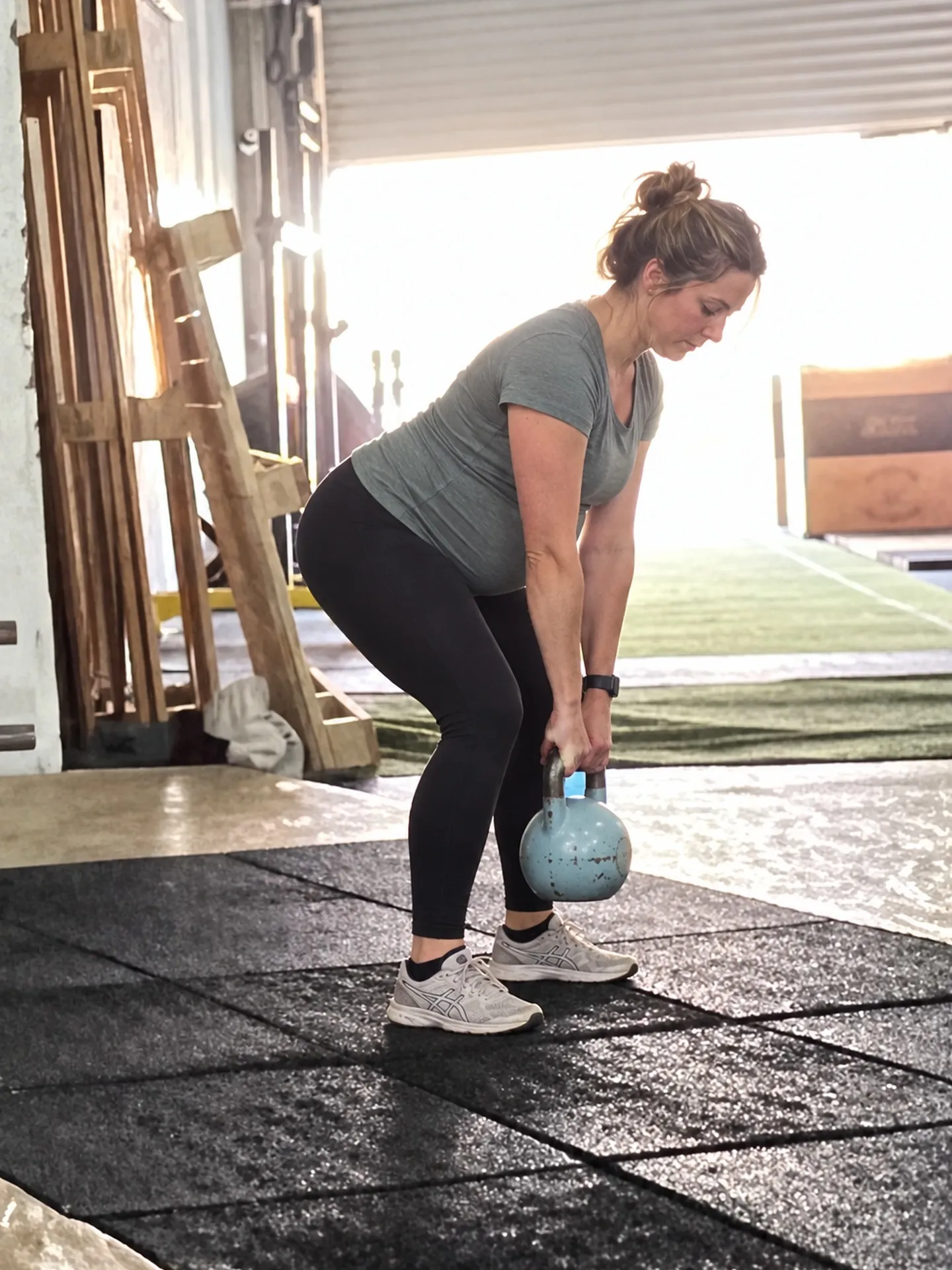 Schwangere Frau beim Kettlebell-Deadlift mit hellblauer Kettlebell