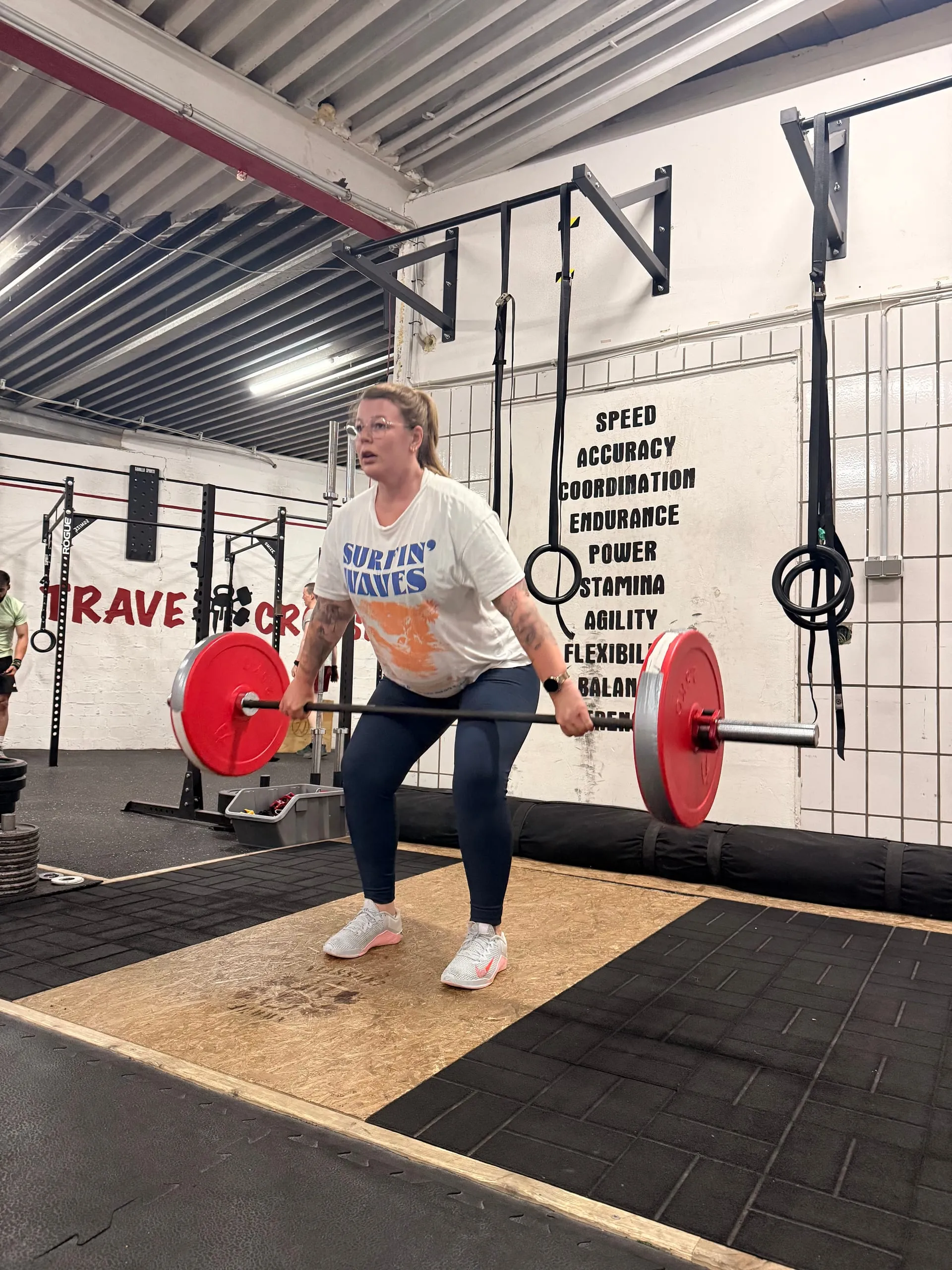 Schwangere Frau hebt eine Langhantel mit roten Scheiben in der Trave CrossFit Box