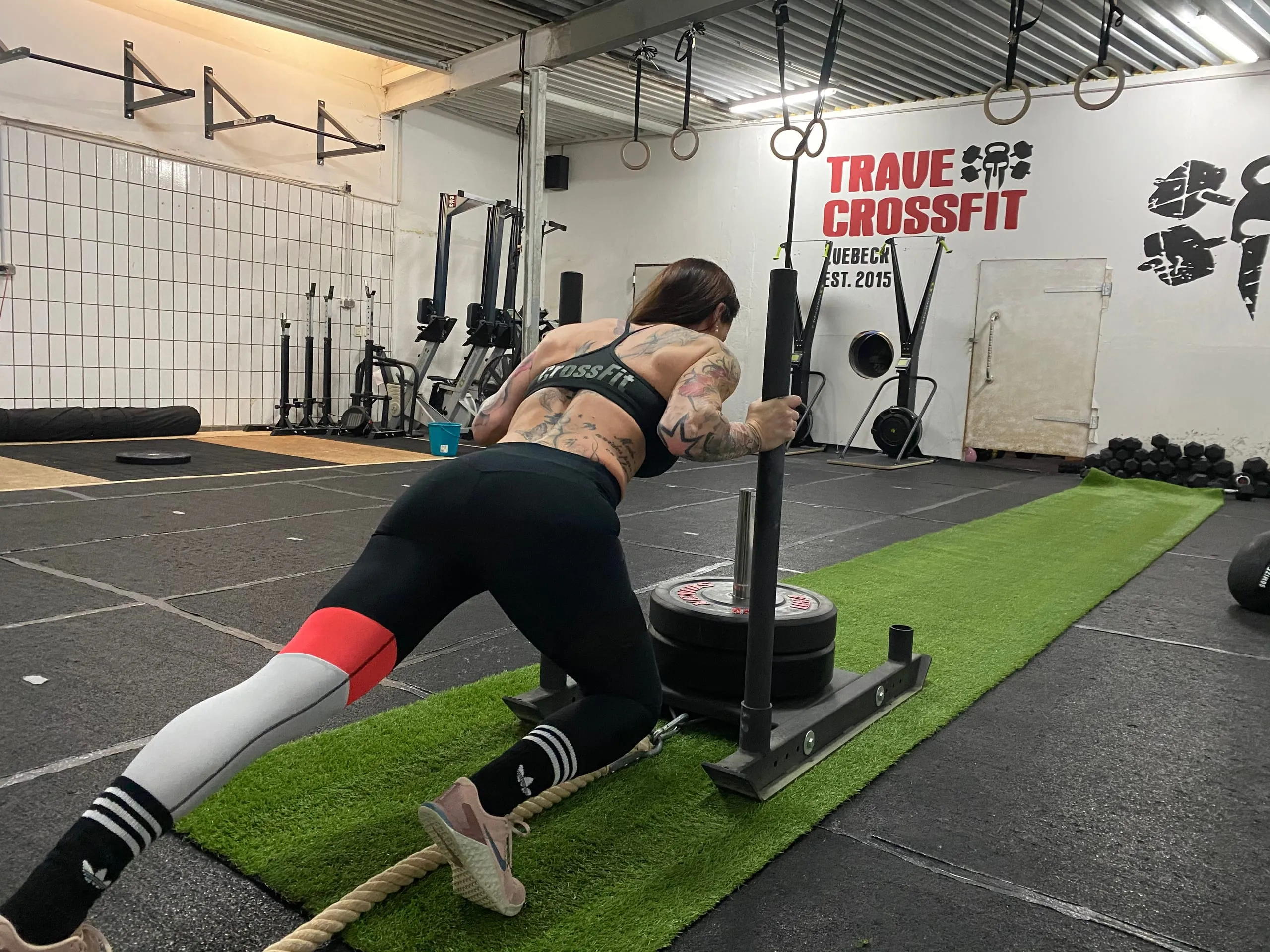 Athletin schiebt einen beladenen Sled über die Bahn in der Trave CrossFit Box